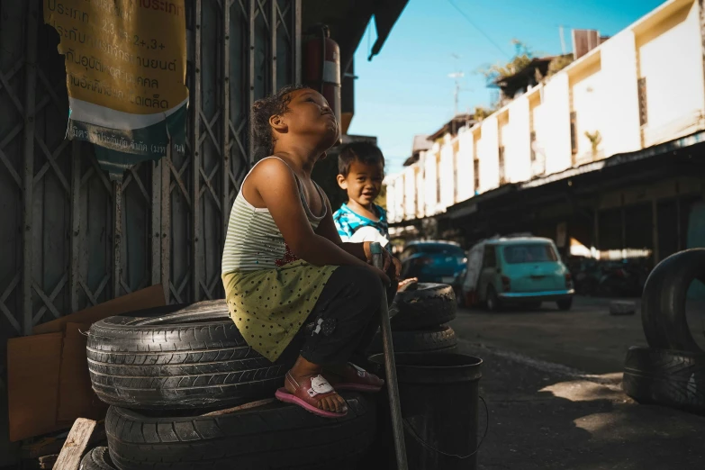 two people sitting on top of large tires in a lot