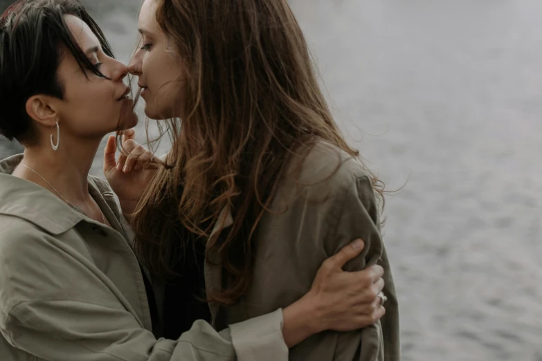 two woman are kissing and one is looking off to the side