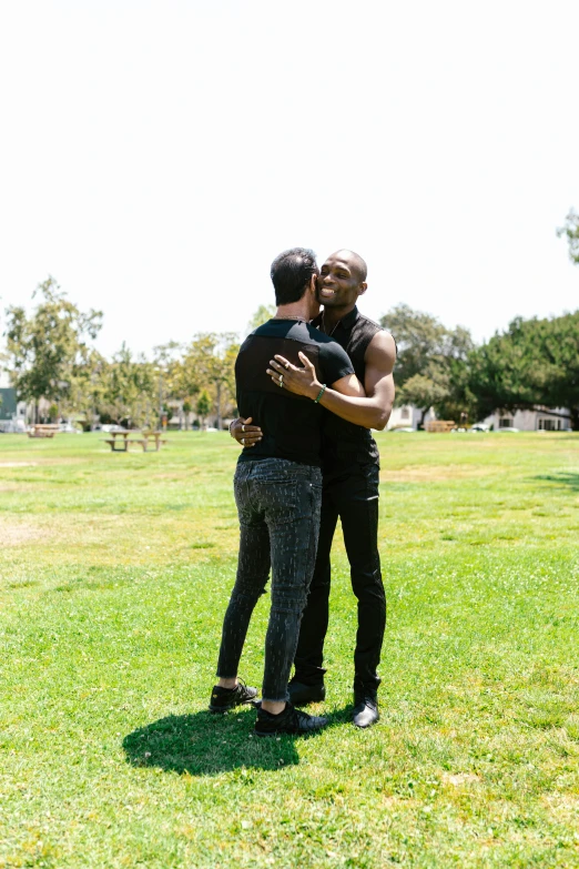 two young men standing on a green field emce