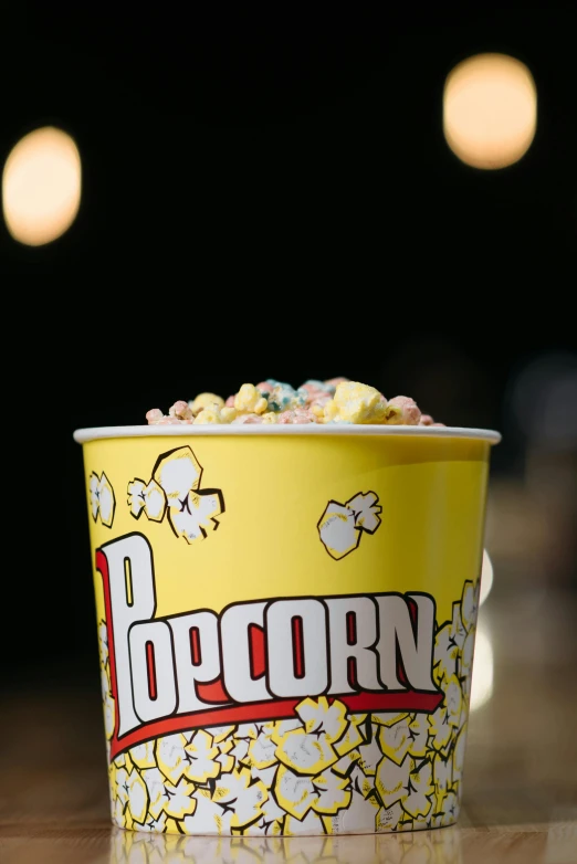 a yellow cup with popcorn on it sitting on a table