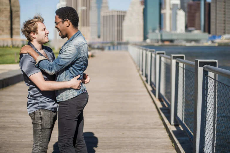 two young men are hugging each other while standing on the dock