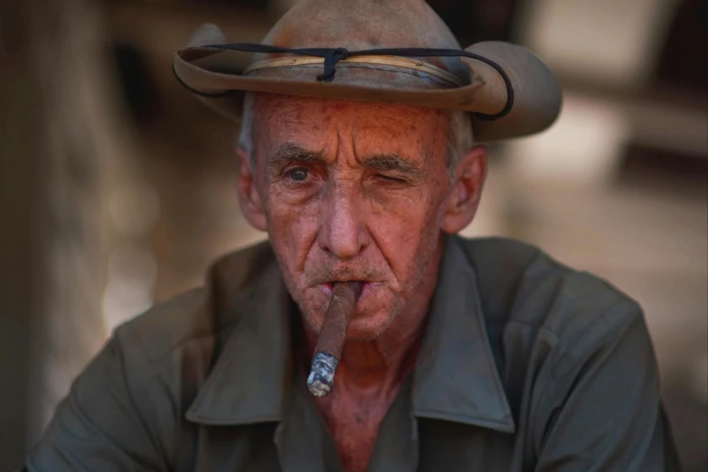 an old man with a hat, jacket, and cigar in his mouth