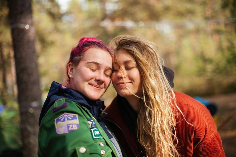 two women standing next to each other in the woods