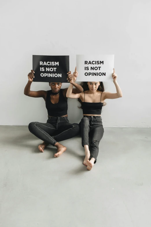 three people sitting on the floor holding signs