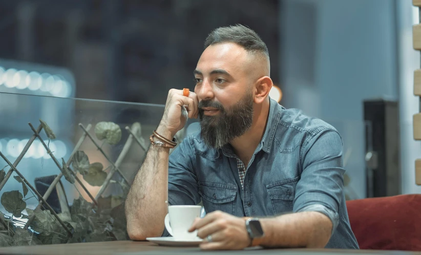 a man sitting at a table while talking on his phone