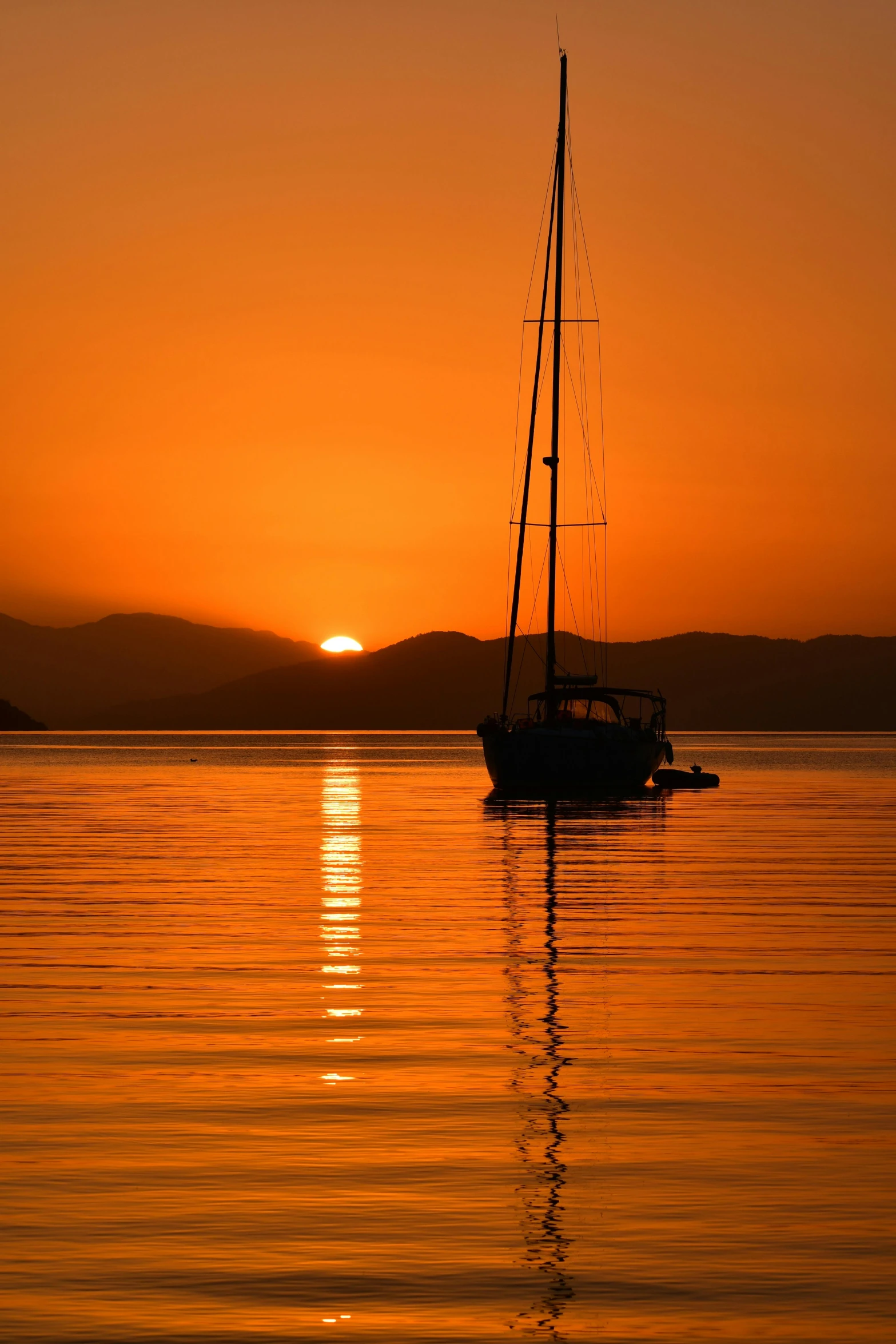 the sun setting behind the water with a boat in it