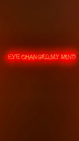 red neon sign on wall saying eye changing my mind