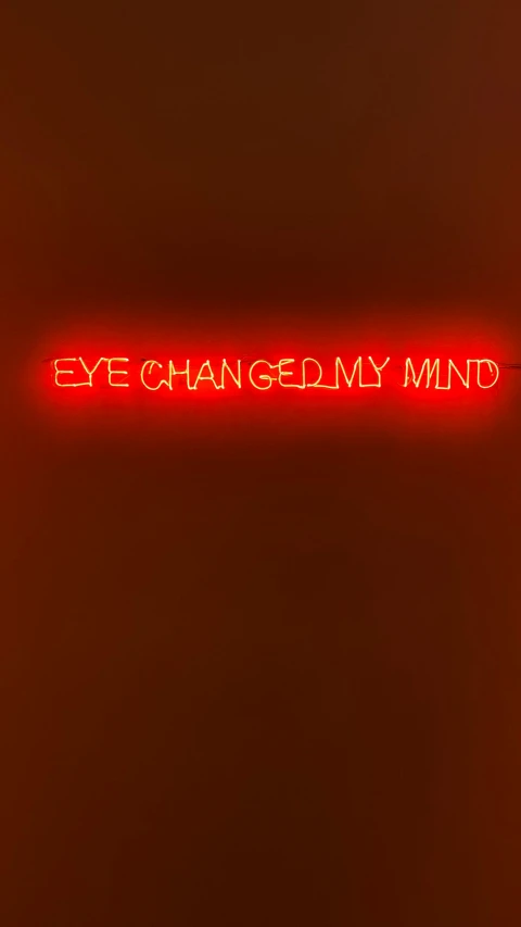 red neon sign on wall saying eye changing my mind