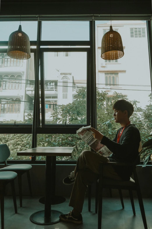 a man sitting in a restaurant reading a paper