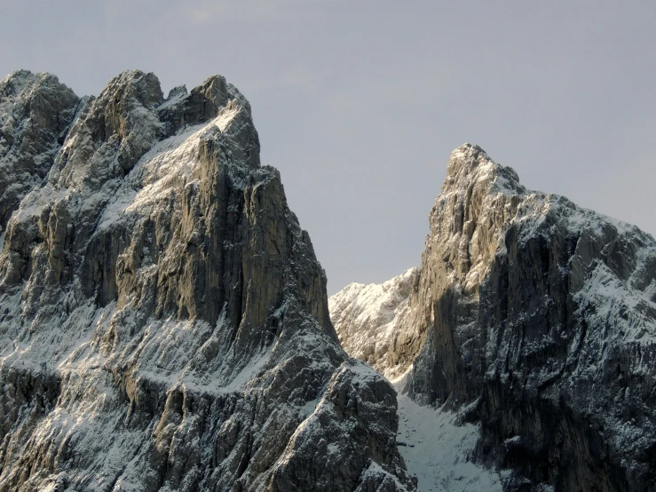 a tall mountain is covered in snow as it stands against the sky