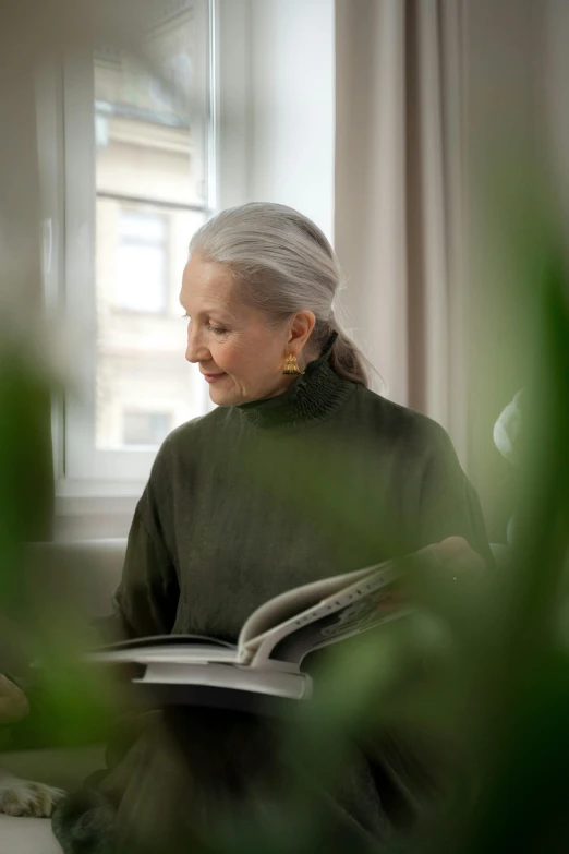 an old woman reading a book in the room