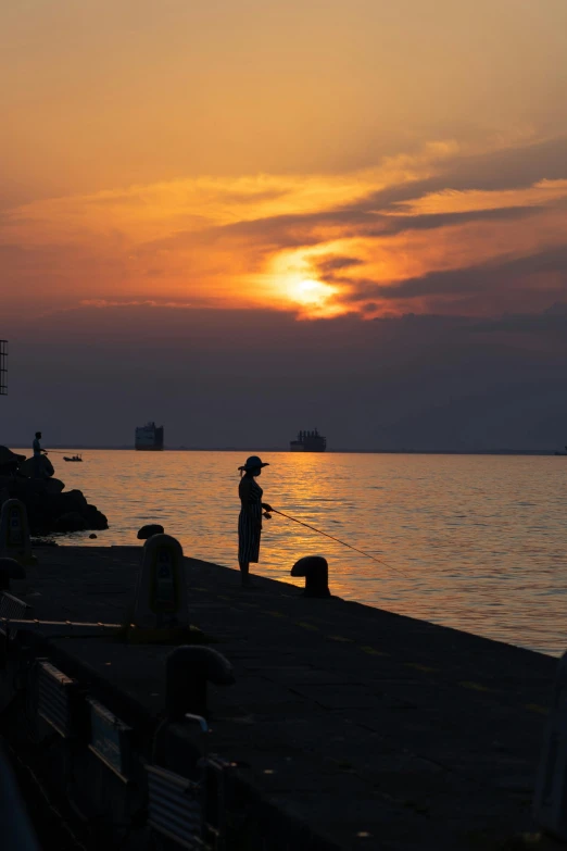 a lone person fishing on the water at sunset