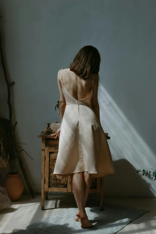 woman in dress standing in front of a small desk