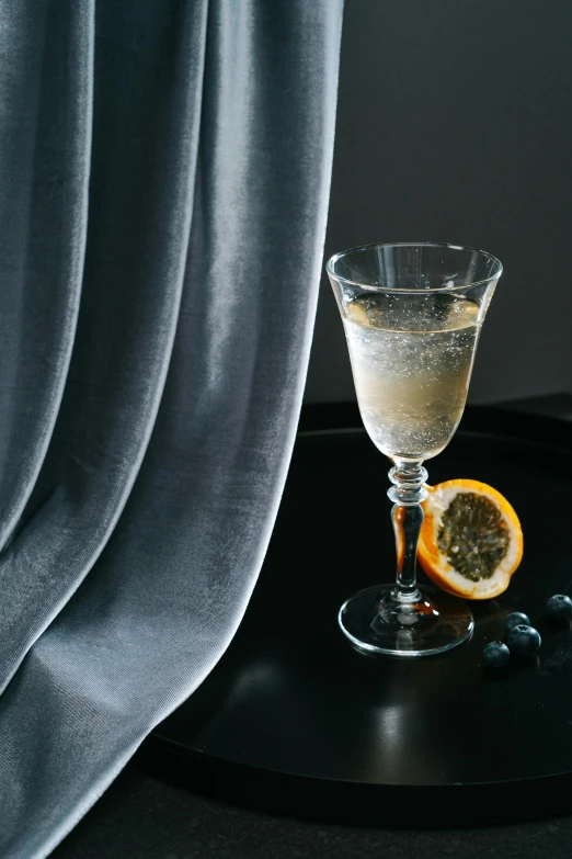 a glass with orange slices on top next to a black table