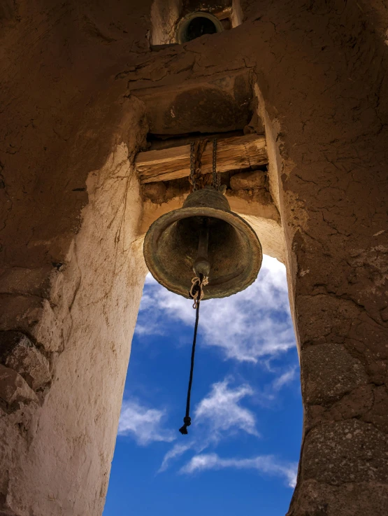 an ancient bell on a wall with the sky in the background