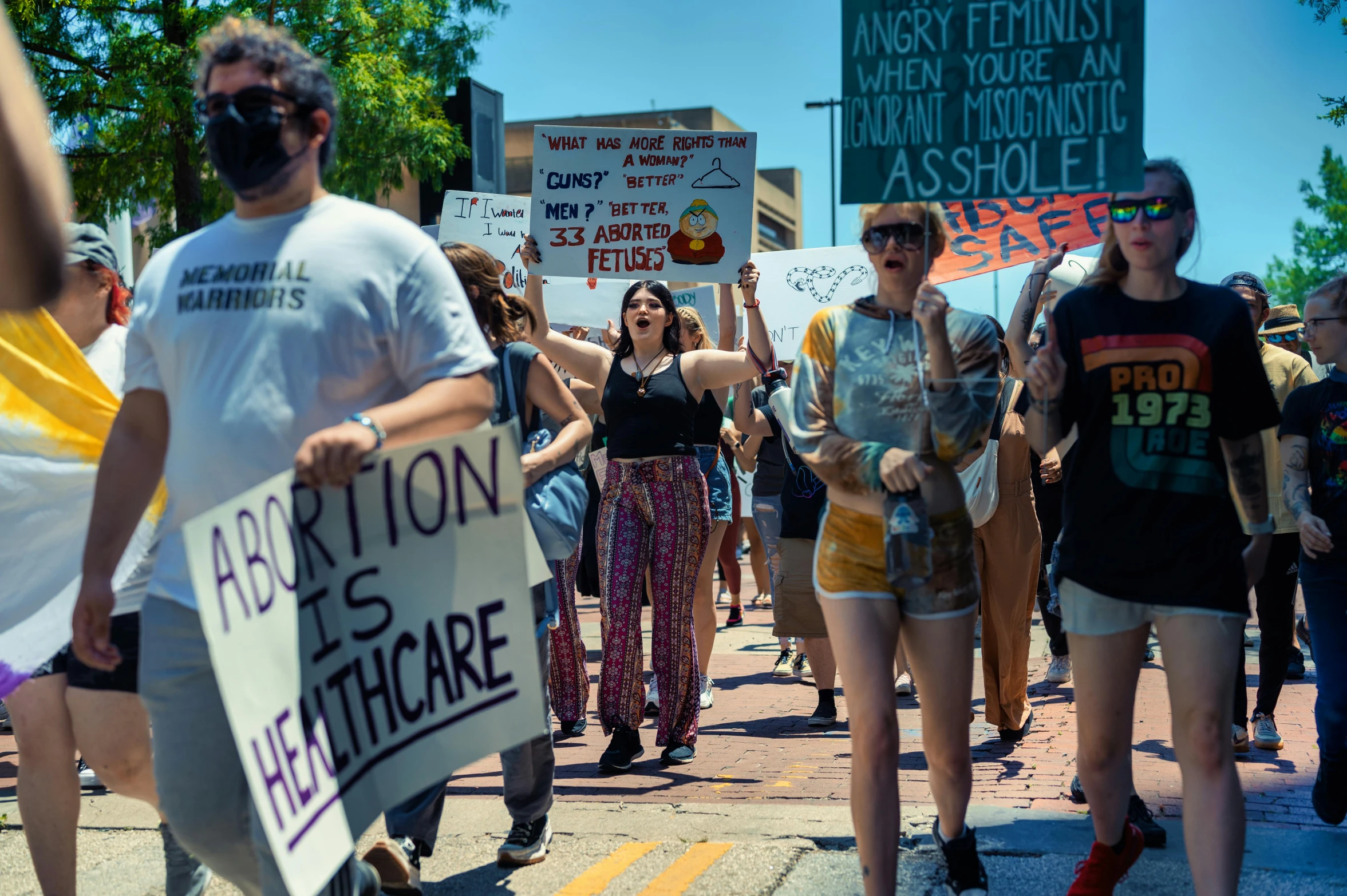 a group of people holding up signs and walking down a road