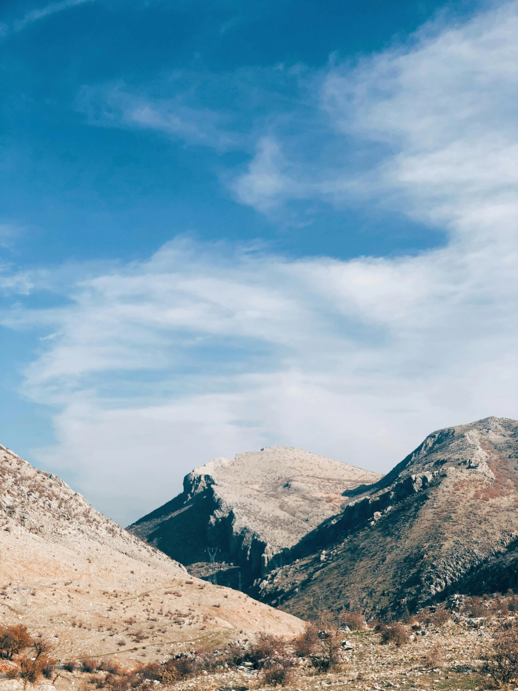 a dirt field in the mountains with a sky background