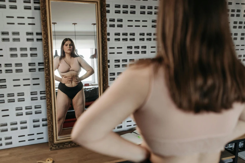 a women is looking in a mirror and she has her underwear tucked down