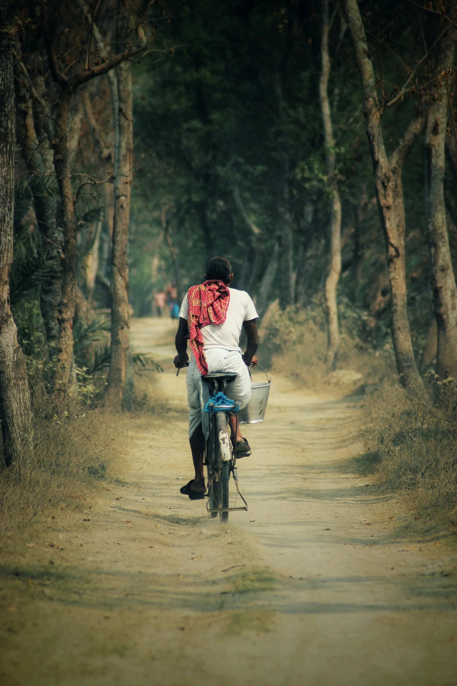 man riding on motorcycle down the middle of a dirt road