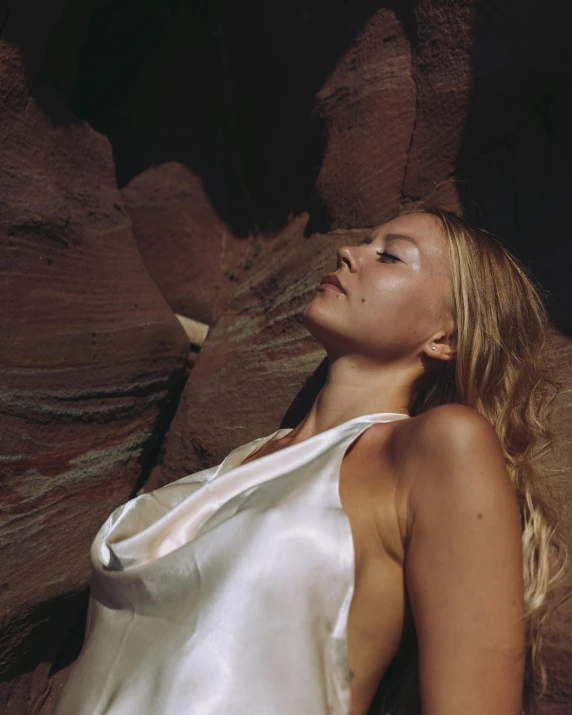 a woman with her eyes closed sitting on a rock