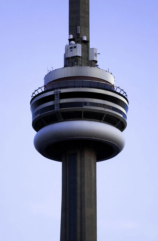 the side of a tall tower with a control tower and clock on it