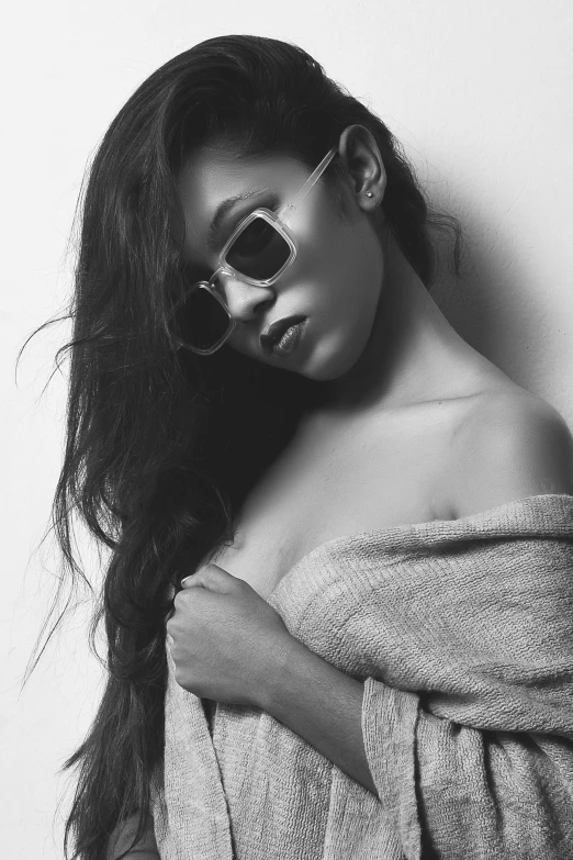 a beautiful woman wearing sunglasses leaning against a wall
