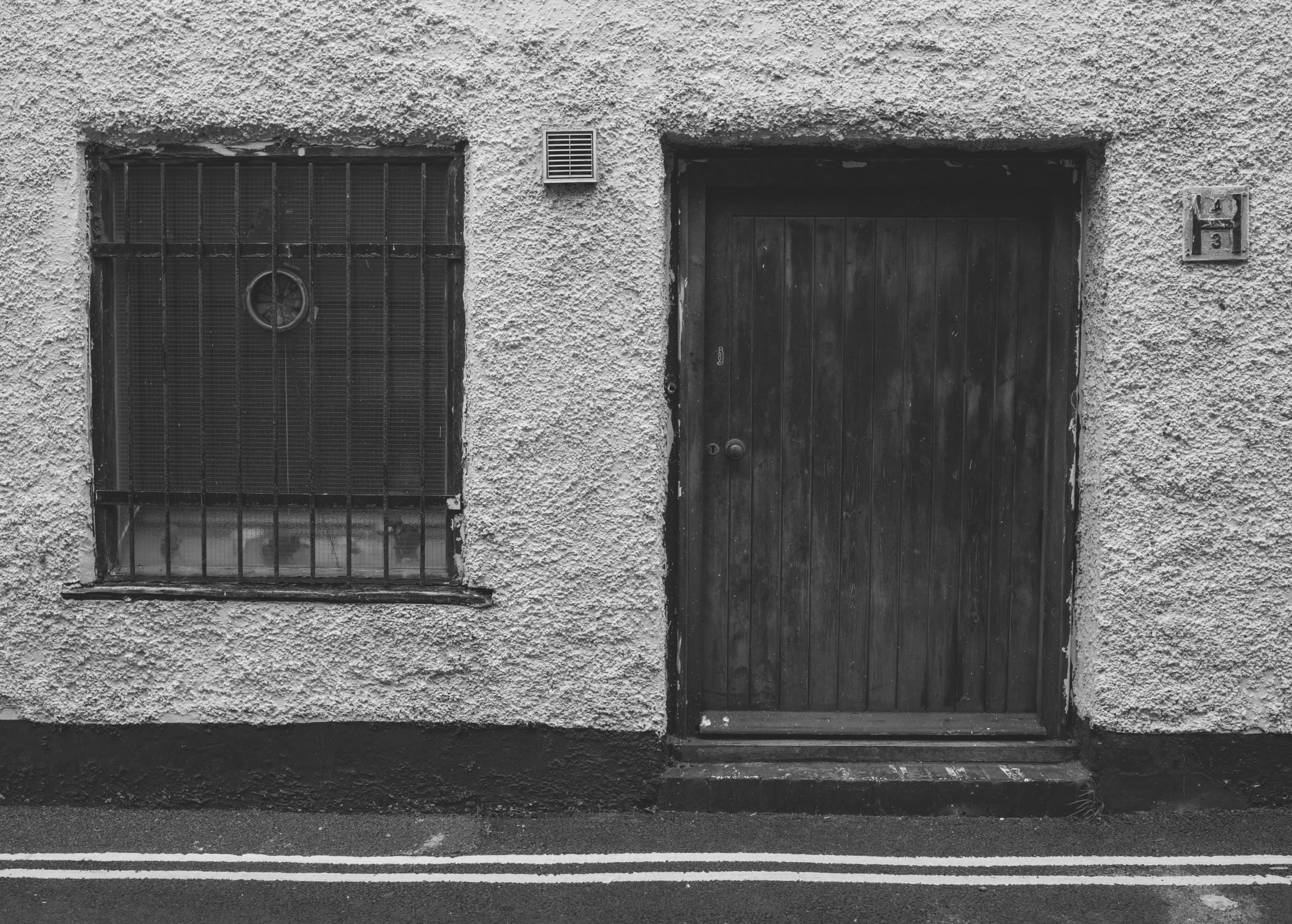 a small door to a white building next to two windows