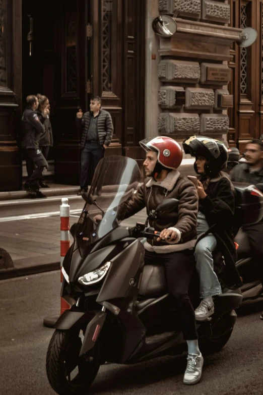 people riding motor scooters through the city while others watch