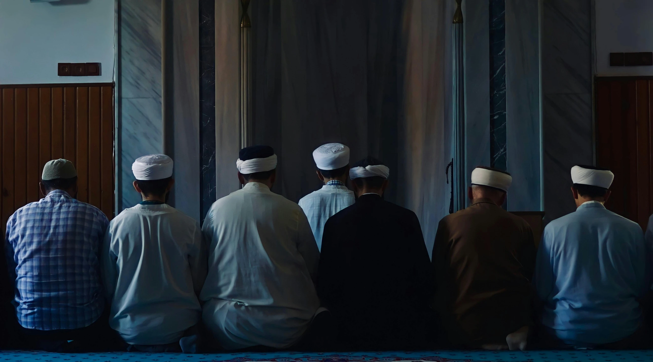 a group of men dressed in white and black sit in a line