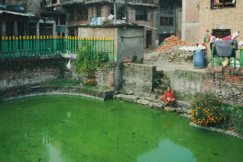 the woman is sitting outside of the house looking at the water