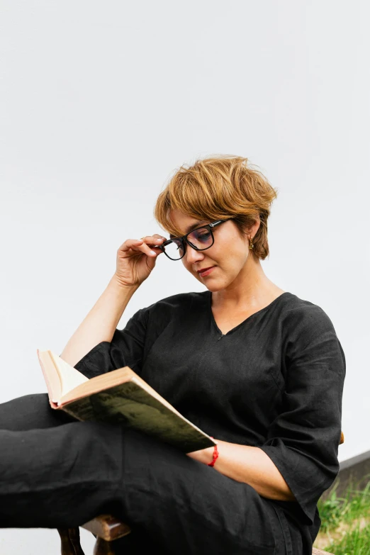 a woman is sitting on a bench reading a book