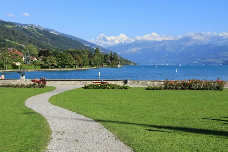 a pathway leading into a lake with mountains in the background