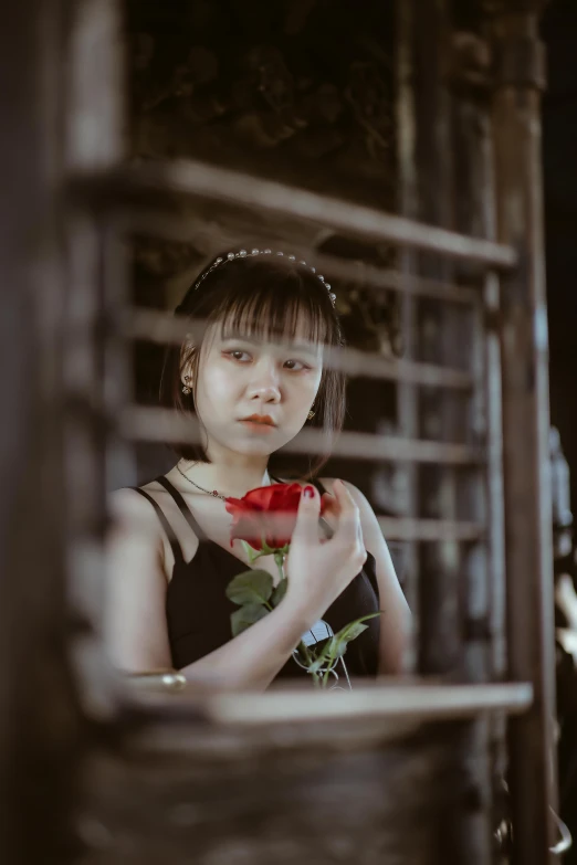 a girl looks out through a window with an elegant dress