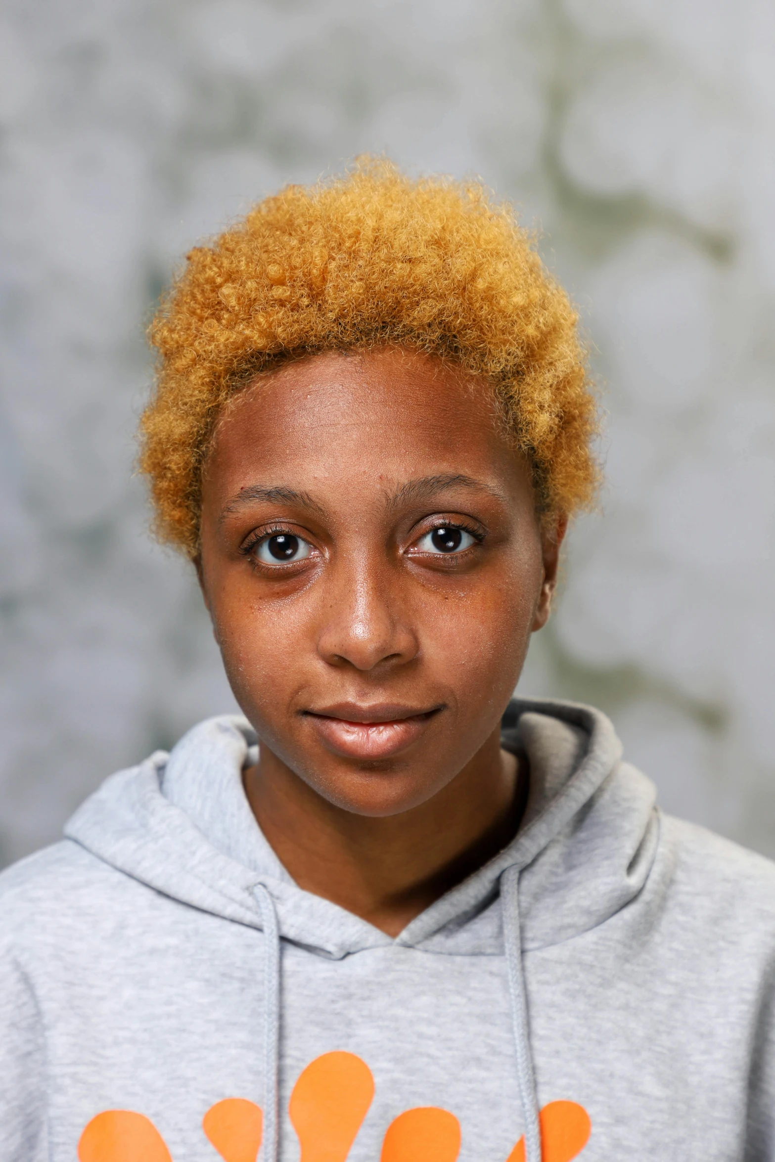 a little girl with a red afro standing in front of a marble wall