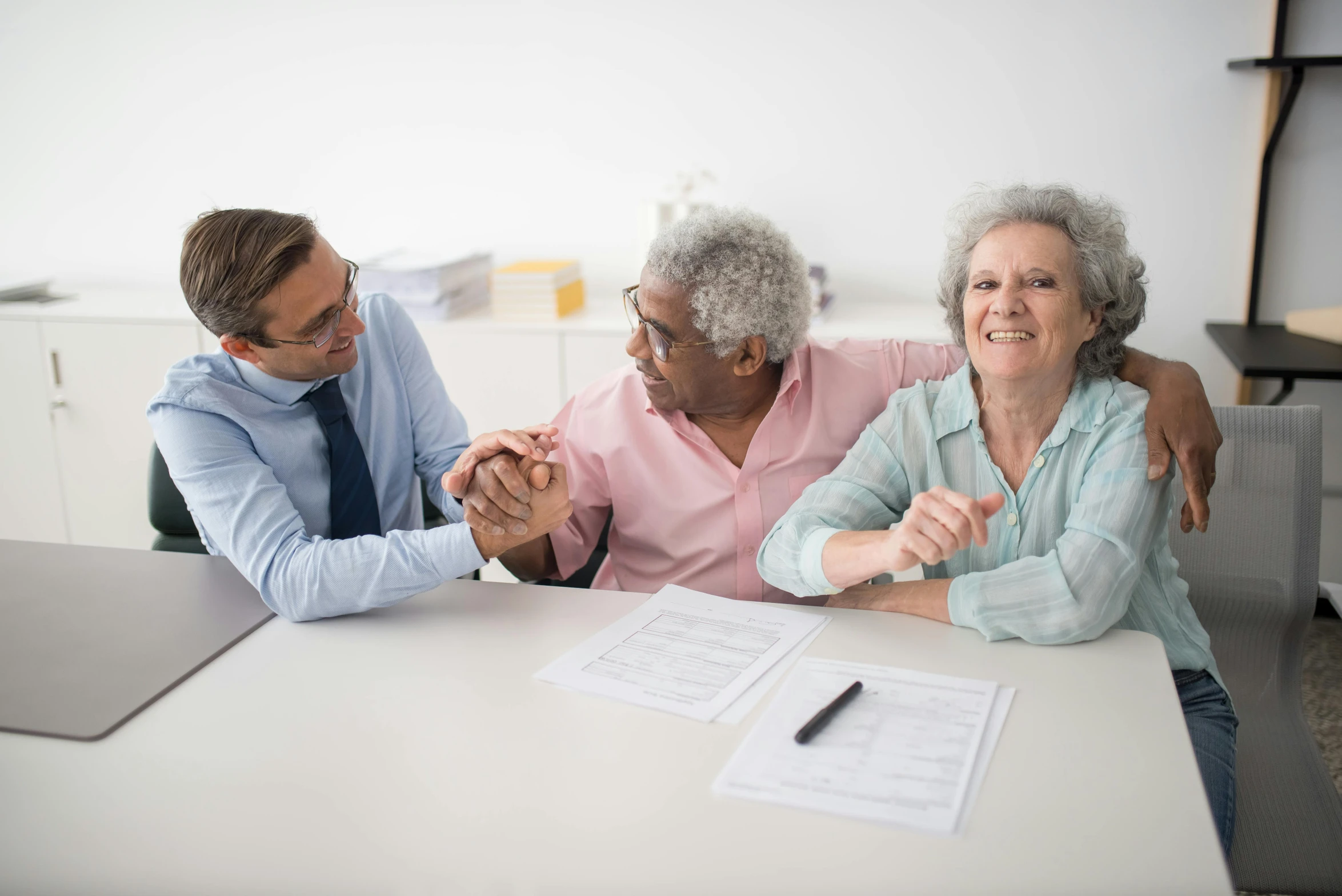 three elderly women are sitting at a table and having a meeting