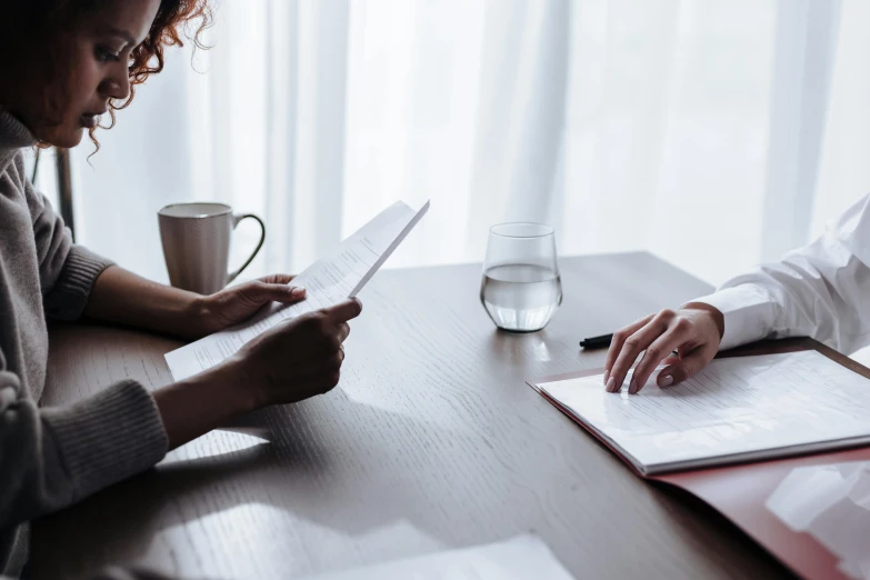 two women are at a table with papers