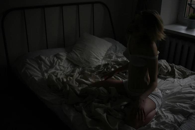a person is kneeling in the dark on the bed