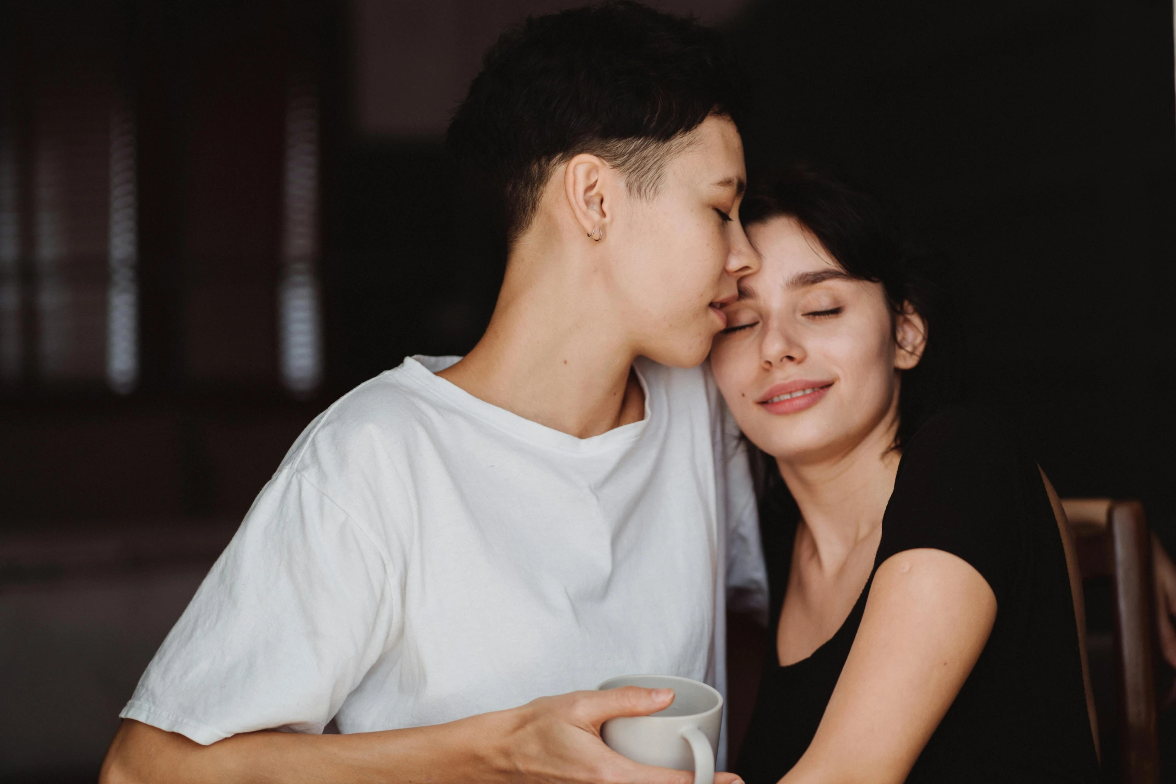 young couple kissing as they hold cups of coffee