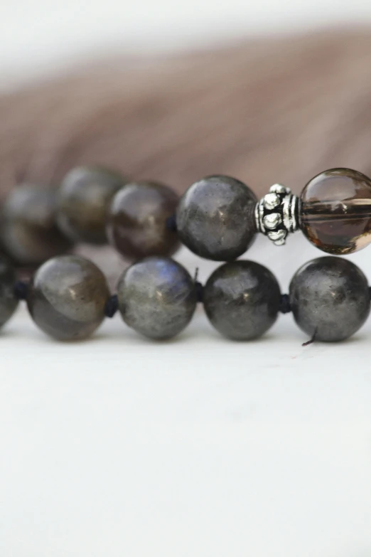 a rosary with two brown beads laying on a white surface