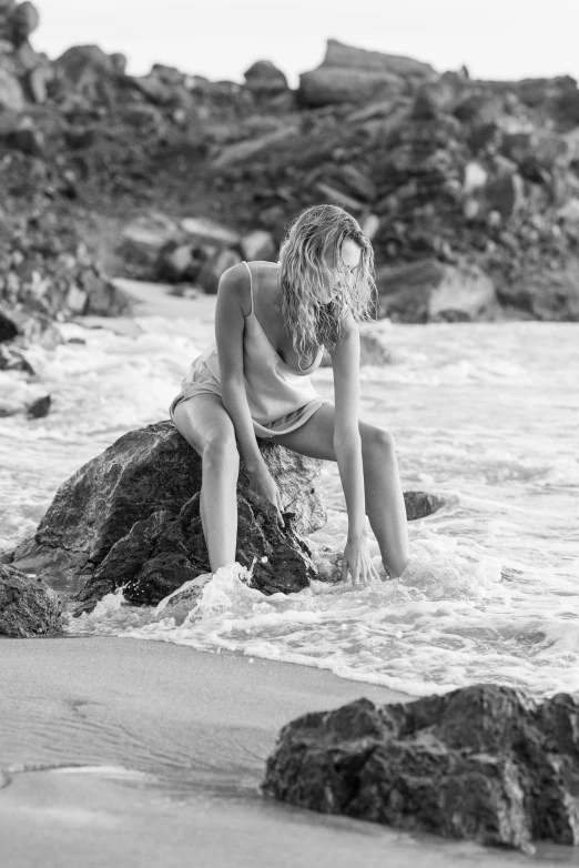 a  sits on the edge of rocks on the beach