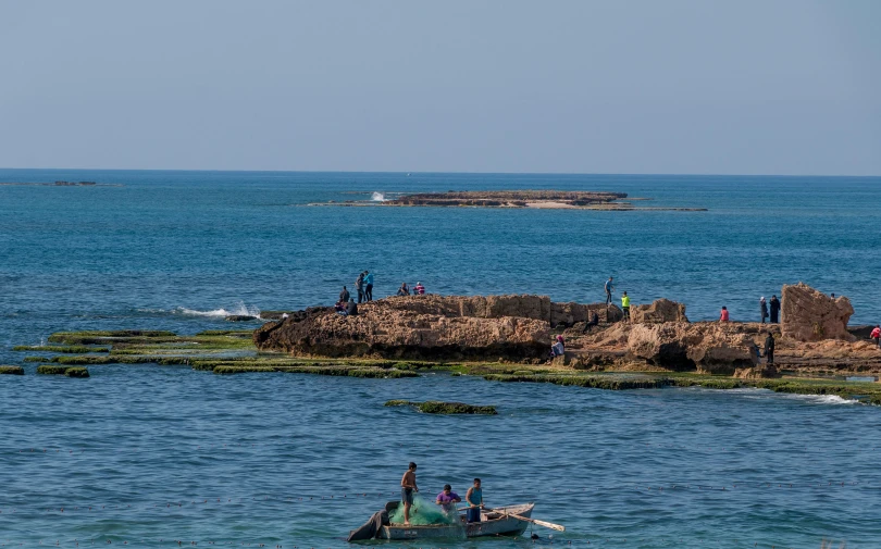 a group of people on small boats next to rocks in the ocean