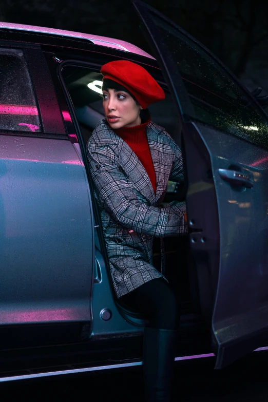 a woman leans out the car window in front of it