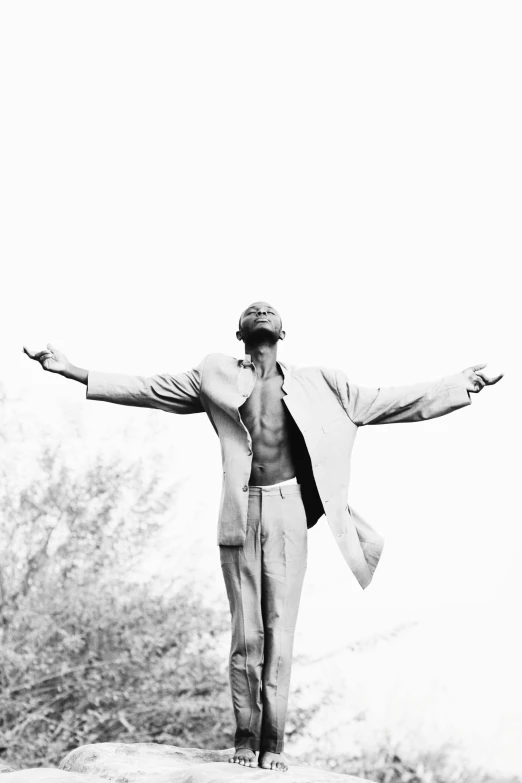 an older gentleman with his arms outstretched, standing on a sand dune