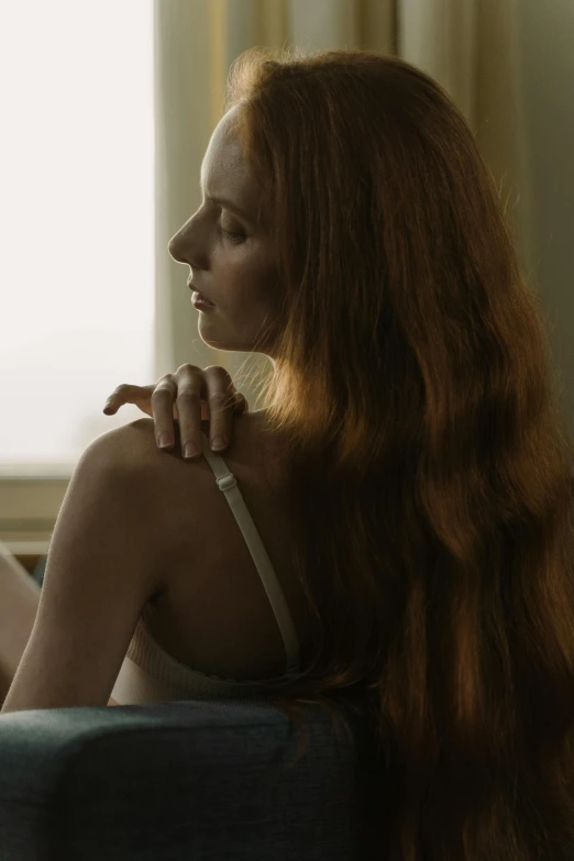 a woman with long hair sitting and looking out a window