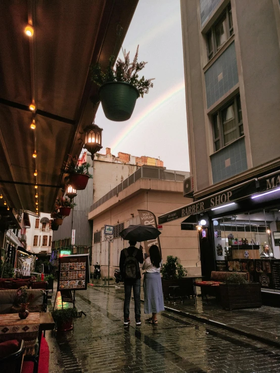 two people standing under an umbrella in a city square