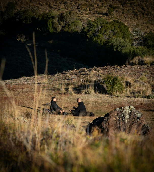 the couple is sitting outside in the meadow with their dog