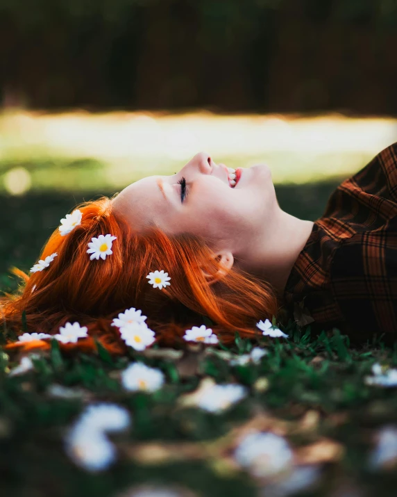 a young lady with red hair laying in a grassy field