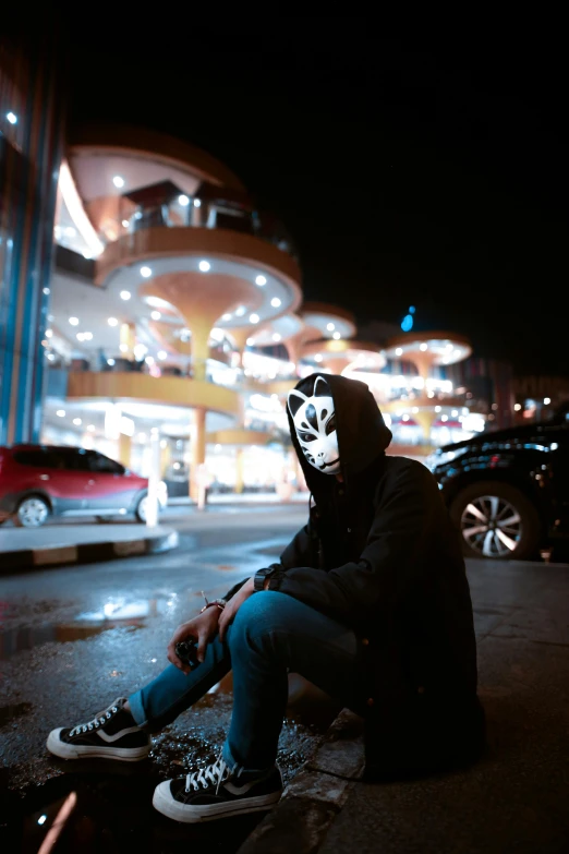 the guy wearing a mask sits on his skateboard