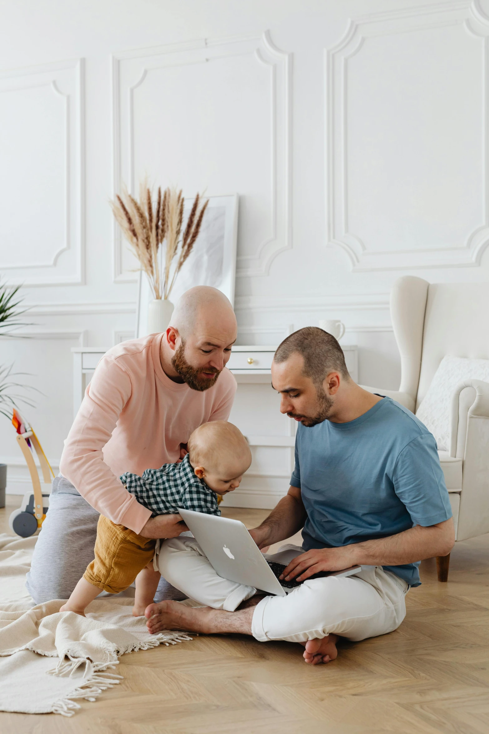 a man holding a baby in his lap and two others sitting down on the floor