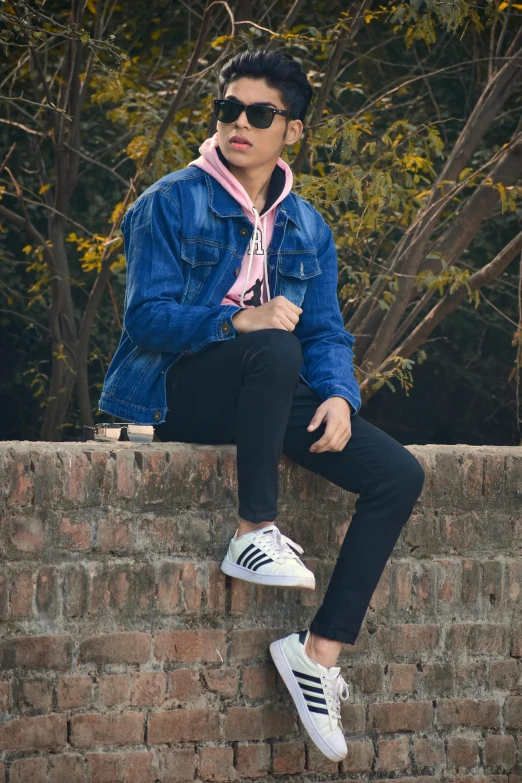 the boy is sitting on a brick wall